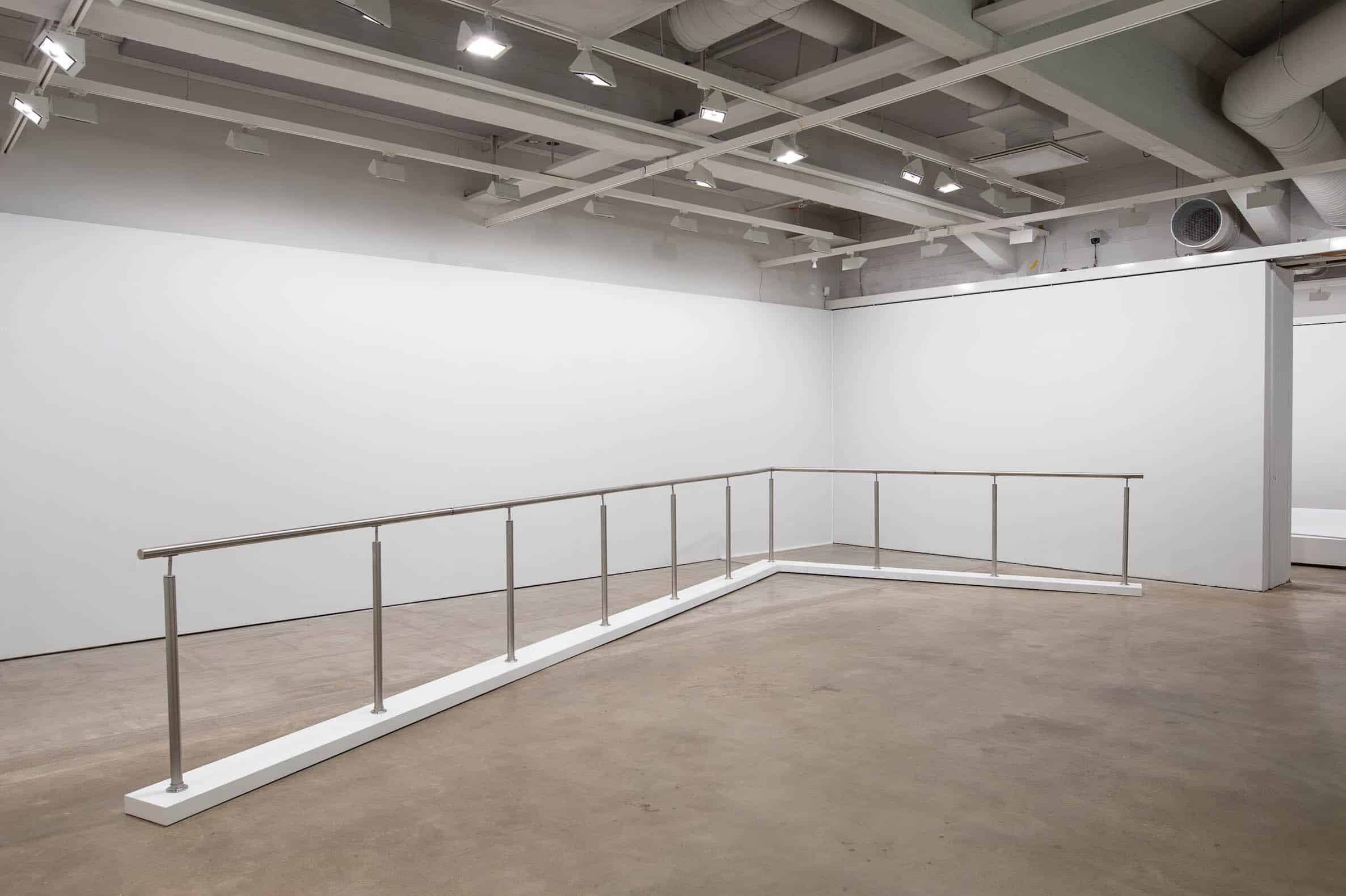 A steel railing which vibrates in an alternating pattern. Rather than guiding or leading the viewer, the railing creates an element of uncertainty. Through the changing mechanical movement, the railing suggests a scene in a mobile environment, such as a train or a ship.