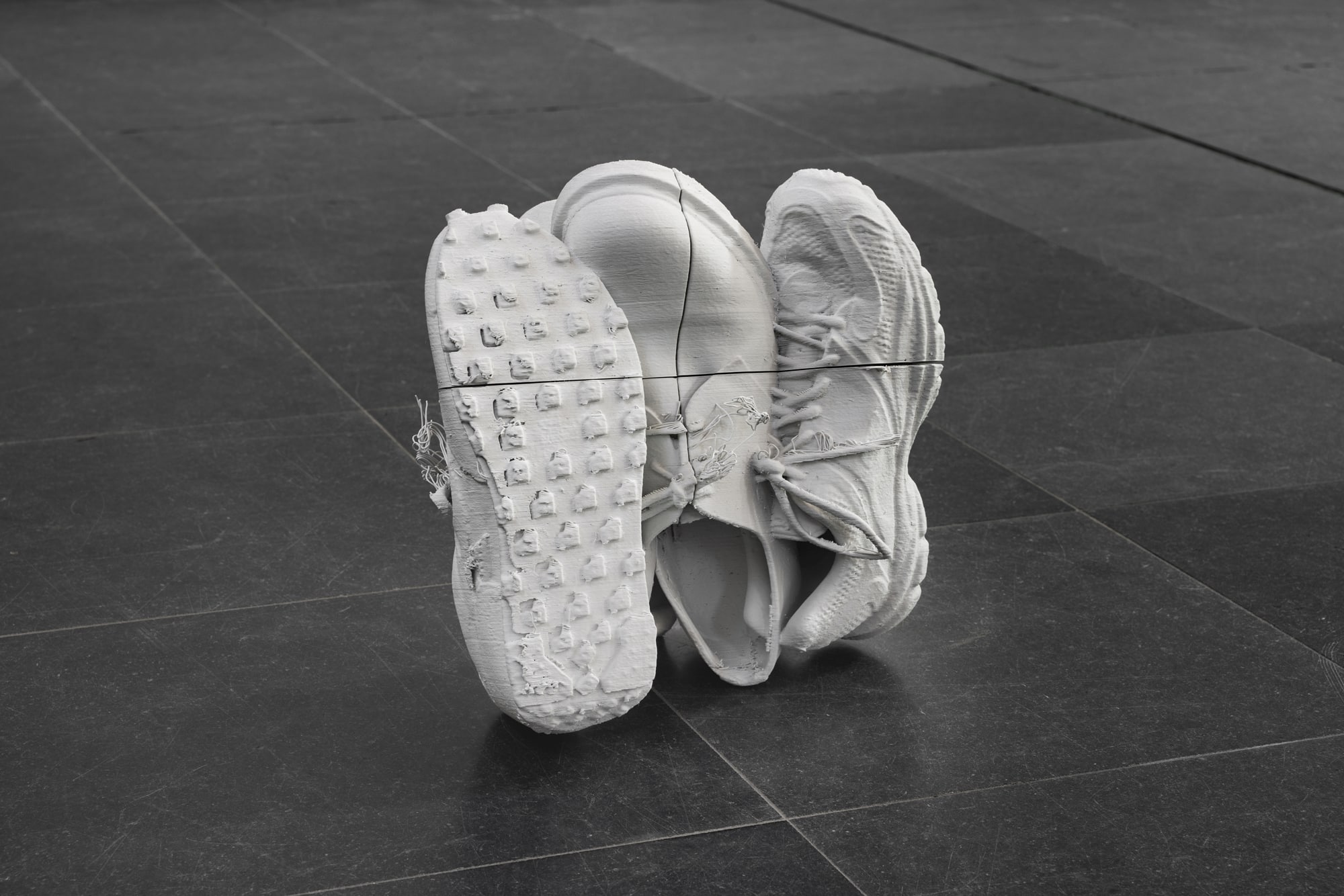 "Pairings" continues Kindermann's exploration of order and chaos, while shifting his attention to the disruptions of perfection in digital processes. The shoe-stacks are 3D-prints, unnaturally joined together and covered with digital noise and sharply cut apart, like a 3D-puzzle revealing its machine-production process. Kindermann scanned some of the singer’s shoes from his performance "Choir Piece" and re-assembled them as pairs and groups. Like a disrupted reality, the intertwined images of the scan force the printer into its own interpretation, creating unforeseeable digital noise. Referring to the singers’ missing bodies in times of pandemic all fragments echo each other as separate parts of a larger whole.