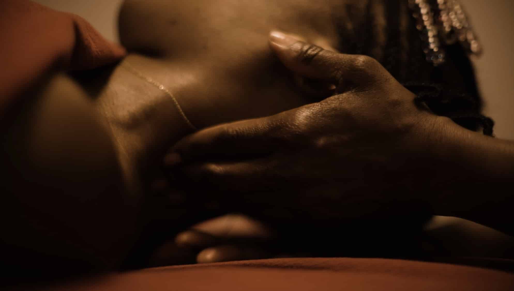 A close up image of the artist receiving massage therapy. Her neck is being massaged by the hands of the therapist and her face is out of view, head tilted away from the camera.