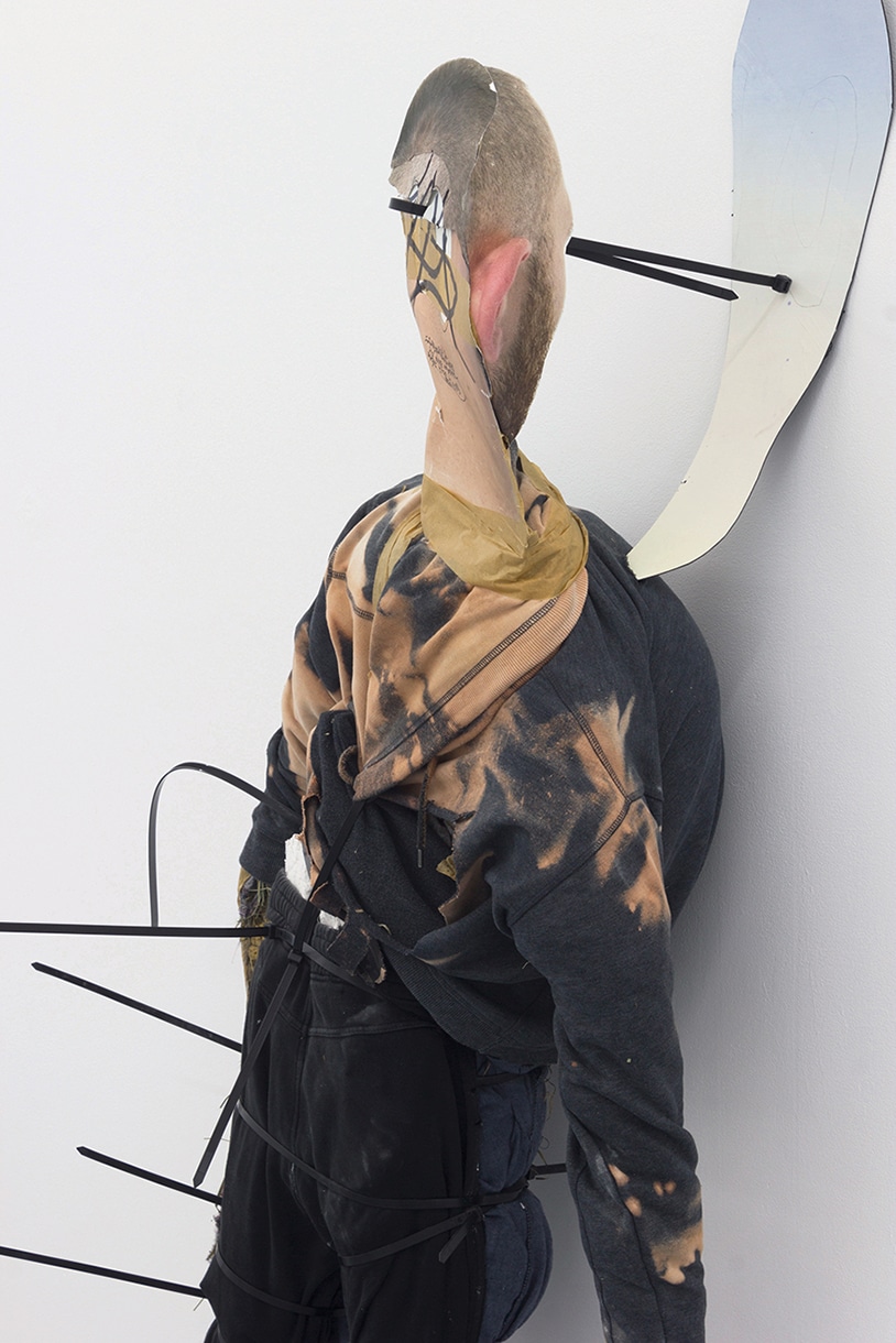 figurative sculpture made of stuffed clothing staring at an empty picture