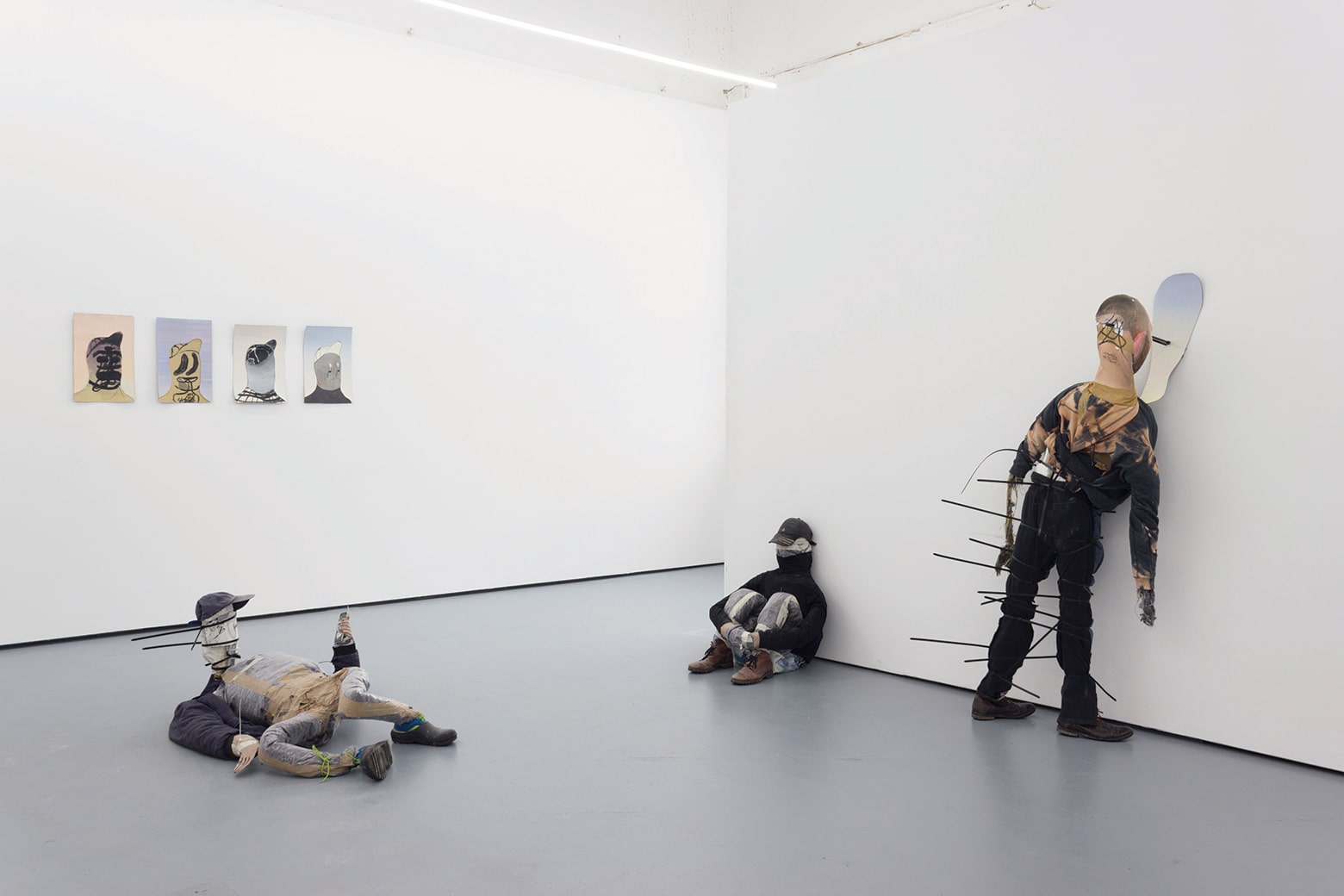 Three figurative sculptures made of stuffed clothing in a gallery show