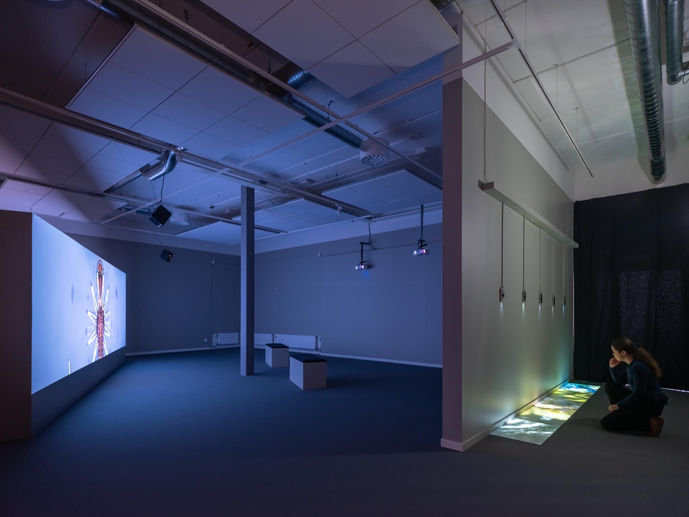 The Other Shore posits a poetic reflection about the Atlantic as a space of transit between the different shores of this ocean that link histories of diaspora, colonization, and the mystery of liberation by navigating to an “other” place, as well as the horrors of captivity awaiting those who are shipped against their will and the voyage back to their homeland. Hjelm’s multimedia syntax, produced by the edited correlation of images, texts, music, and song – media often separated in purist, autonomous notions of language inherited from modernism – comes together in a hybridized whole, like a poetic equivalent of our polarized daily lives. As a result, The Other Shore has a powerful semantic and narrative drive that makes it overflow from the internal structure of linguistic systems to the outside world, with which it poetically connects. This outflowing does not, however, result from a linear edition of sounds and images succeeding one another in a given sequence. There are four simultaneous projections, two by two, on the front and back of the screen, which show on one side audio and visual records of literary and musical works – people and landscapes – recorded on the shores of the Atlantic, combined in flows that do not always fit together logically. On the other side of the screen, projections of watery images evoke the fluid waterway formed by the shores that delimit the Atlantic like a gigantic ocean web that still enables the mass geographic circulation of human beings. A history that cannot be fathomed in the sphere of discourse, but which can be experienced here on a poetic plane.”