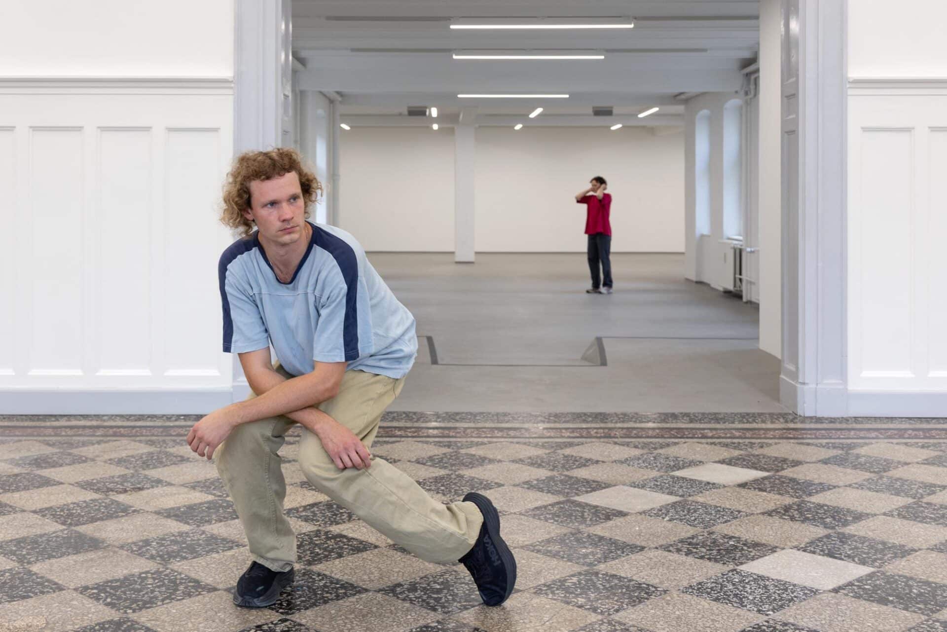 Two dancers perform to the same piece of music, each in a separate room. While the audience is free to move between the spaces, they can only watch one dancer at a time, witnessing two parallel choreographies unfold in solitude.