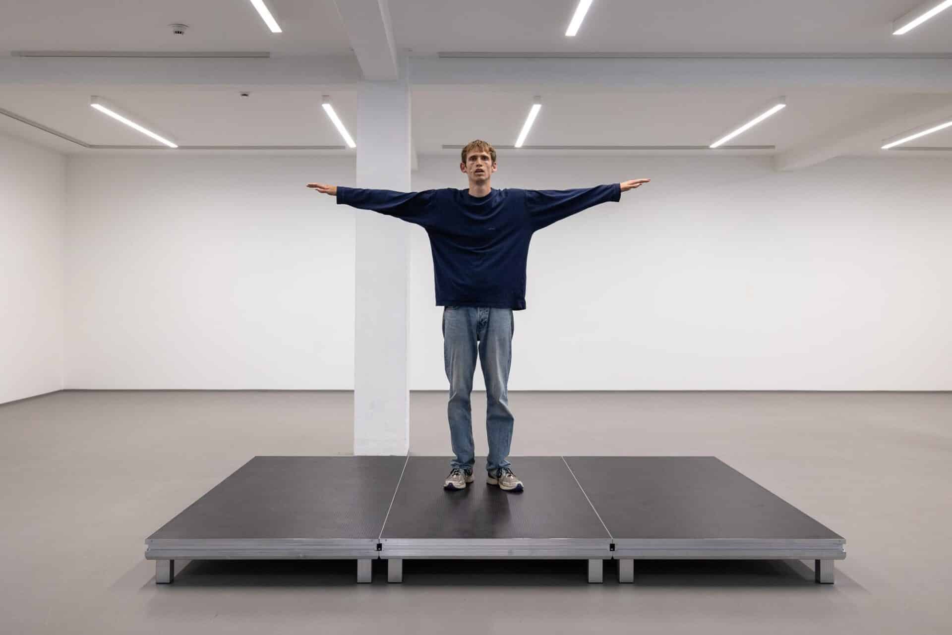 A solo dancer on a platform performing repetitive movements from the dance style Locking, interspersed with monotonous, recited storylines.