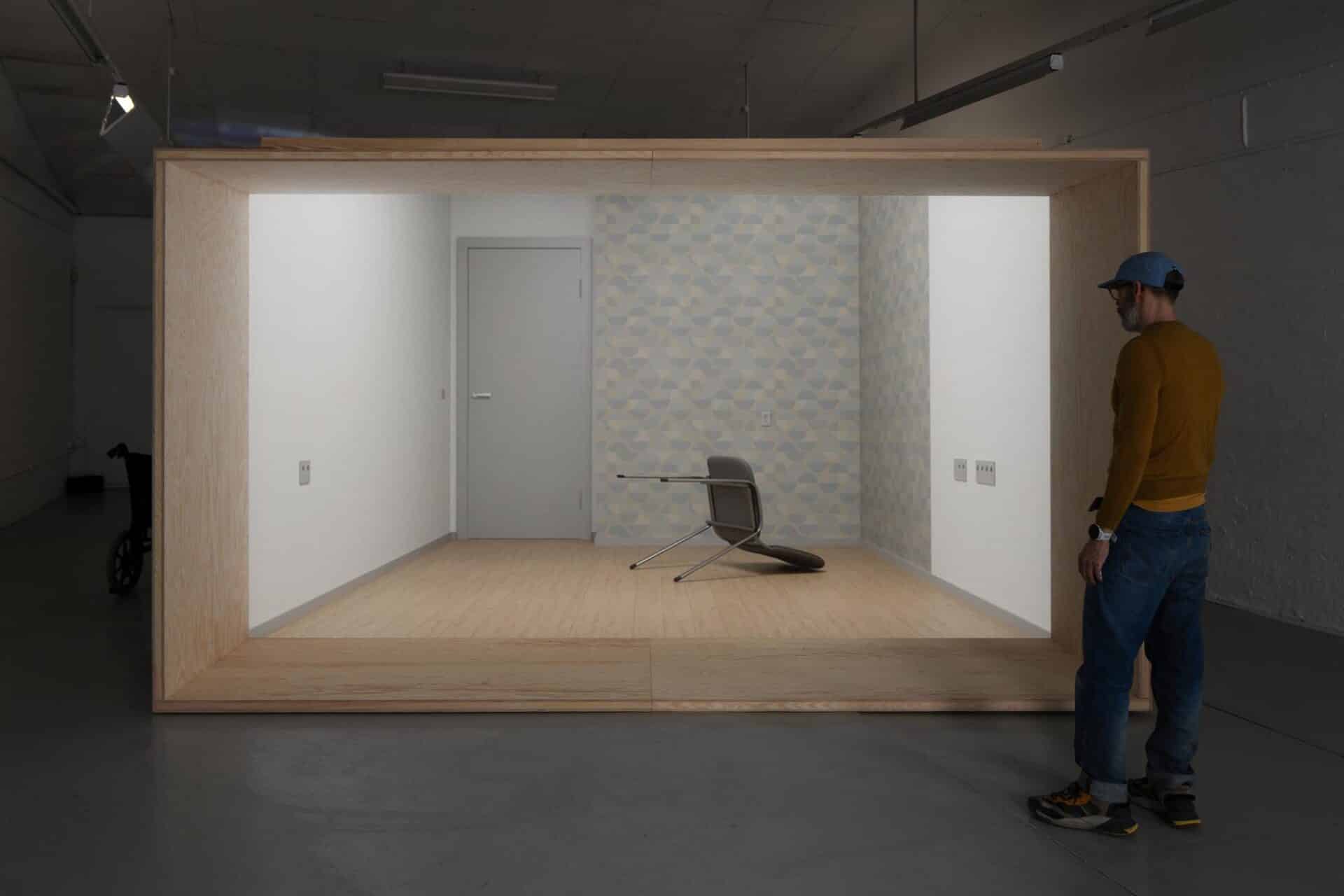 Say It Again is a video installation presented within a large wooden crate standing in the middle of the floor, functioning as a room within a room. Inside, an 8-minute 3D-animated video is set in a clinical, institutional scenography. In this digital space, a single stacking chair is moved by invisible forces: tipping, spinning, sliding, and falling in rhythm with a minimalist soundtrack of a flute, two chords on a piano, and the sound of someone humming nearby. Choreographed into a dance.